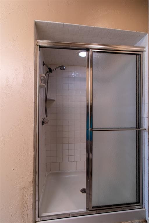full bath with a textured wall and a stall shower