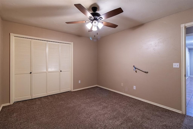unfurnished bedroom with dark carpet, baseboards, and a closet