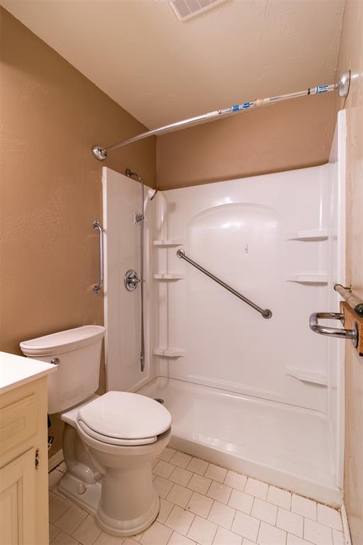full bath with vanity, toilet, tile patterned floors, a shower stall, and visible vents