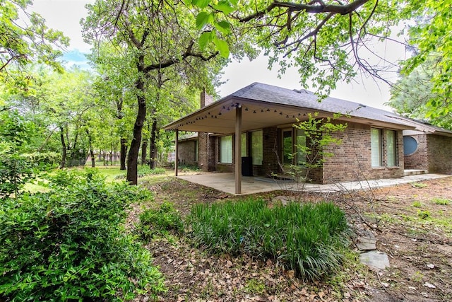 back of property with brick siding and a patio area