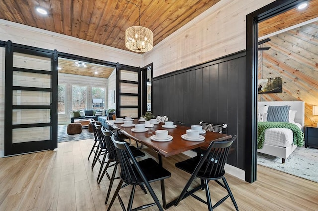 dining area with a barn door, wood walls, recessed lighting, wood finished floors, and wood ceiling