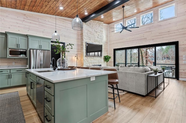 kitchen featuring a healthy amount of sunlight, wood ceiling, a high ceiling, green cabinetry, and stainless steel appliances