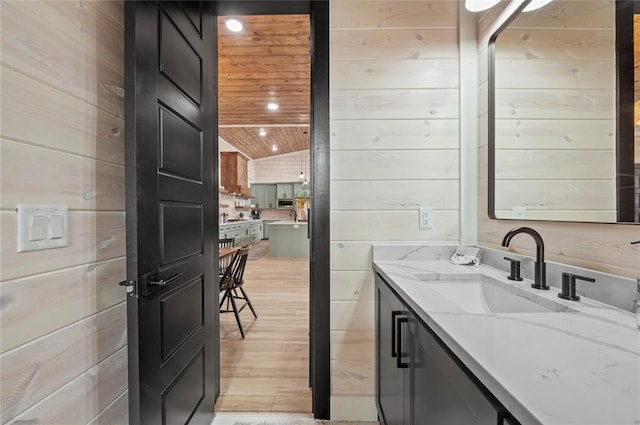 bathroom with vanity, wood walls, lofted ceiling, wood finished floors, and wood ceiling