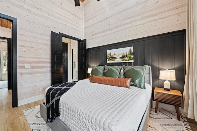 bedroom with a high ceiling, wood-type flooring, and wood walls