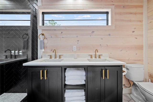 bathroom with a sink, wood walls, and toilet
