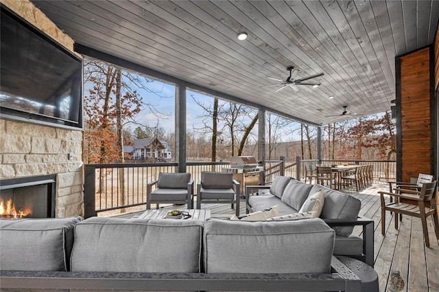 exterior space with a ceiling fan, a wooden deck, outdoor dining area, and an outdoor living space with a fireplace
