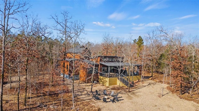 back of property with stairs, a wooded view, and a deck