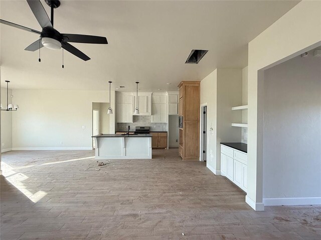 2706 Belle Crossing Dr, Enid, OK 73703 - kitchen featuring dark countertops, open floor plan, a sink, a ceiling fan, and baseboards