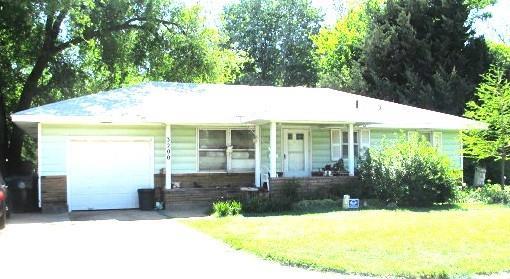 ranch-style home with concrete driveway, an attached garage, covered porch, and a front yard
