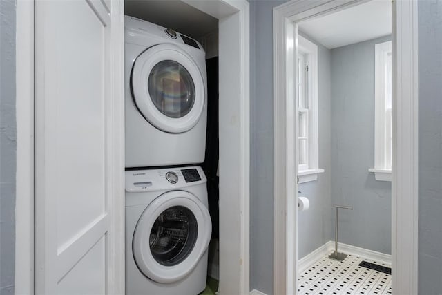 laundry room featuring baseboards, laundry area, and stacked washer / dryer