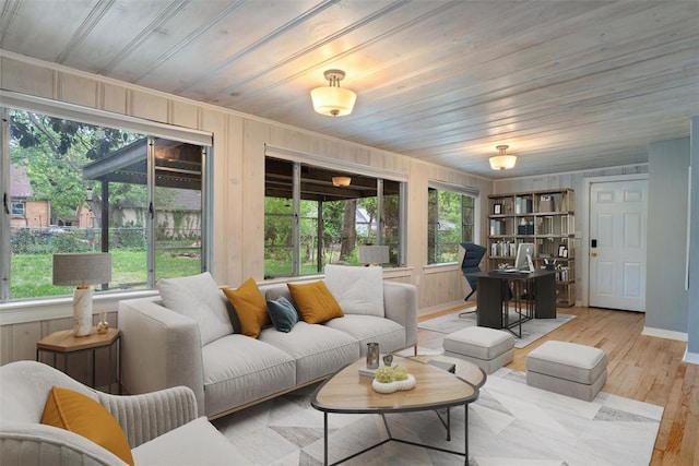 living area with crown molding, baseboards, wooden walls, wooden ceiling, and light wood finished floors