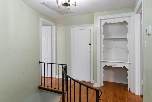hallway featuring visible vents, wood finished floors, and an upstairs landing