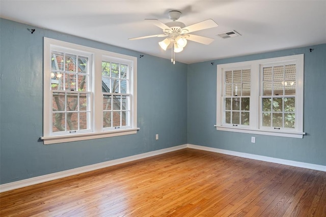 empty room with light wood-style floors, baseboards, ceiling fan, and visible vents