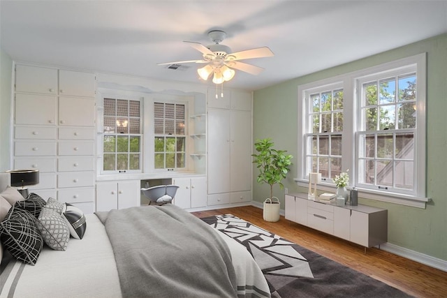 bedroom featuring a ceiling fan, baseboards, visible vents, and wood finished floors