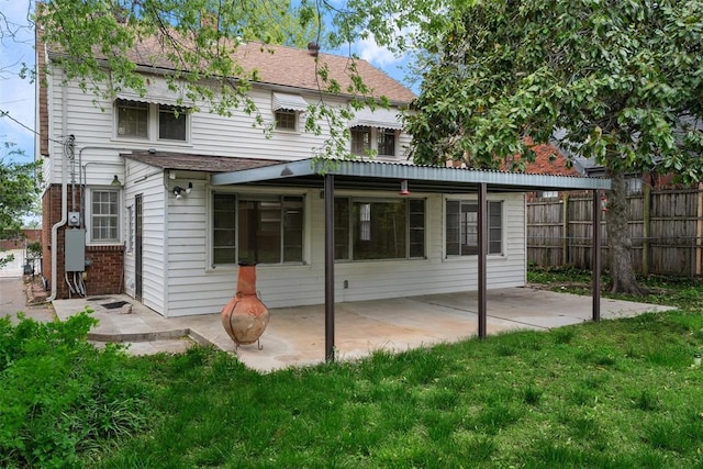 rear view of house featuring a patio, a shingled roof, a lawn, and fence