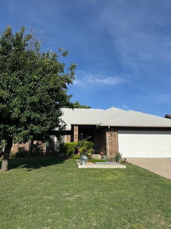 single story home featuring a garage, a front yard, concrete driveway, and brick siding