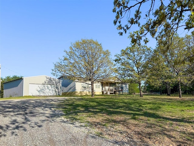 view of front of home with an outdoor structure, gravel driveway, a front lawn, and a garage
