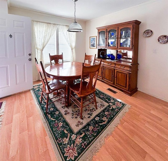 dining space with light wood-style floors, visible vents, and ornamental molding