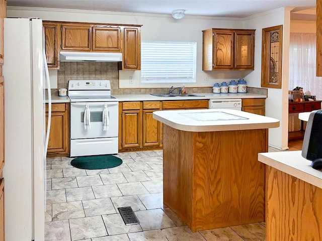 kitchen featuring brown cabinets, under cabinet range hood, light countertops, a sink, and white appliances
