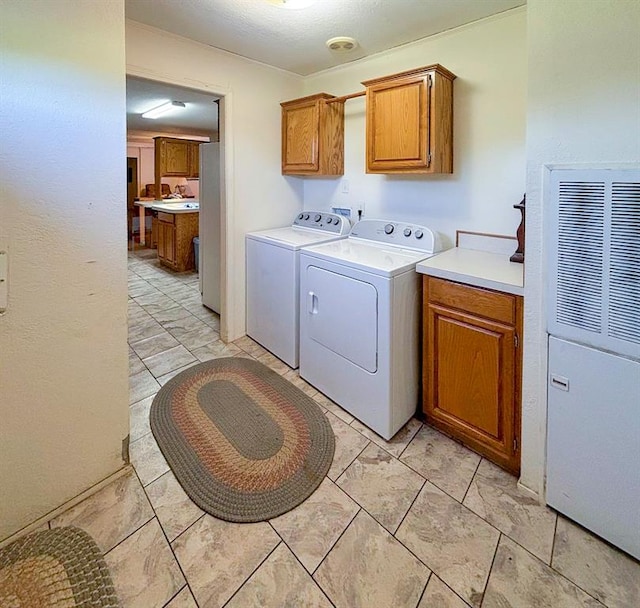clothes washing area featuring washer and dryer, cabinet space, and a heating unit