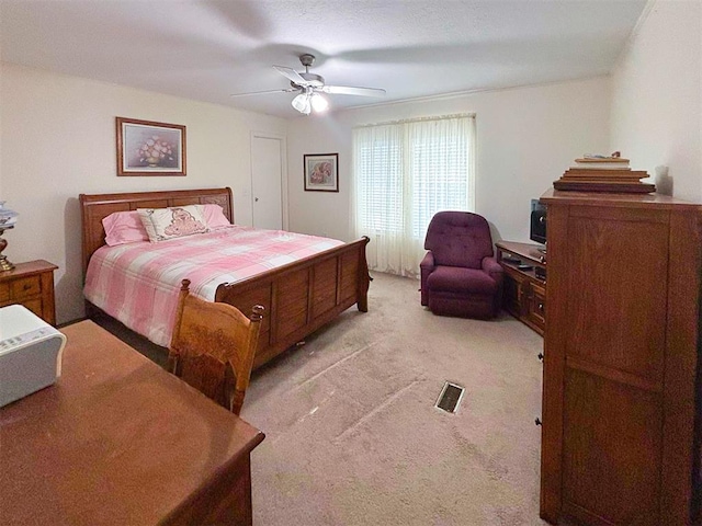 bedroom featuring visible vents, a ceiling fan, and light colored carpet