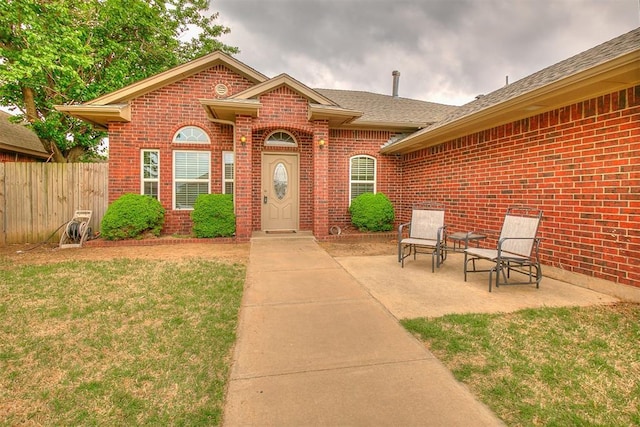 716 SW 149th Pl, Oklahoma City, OK 73170 - property entrance with brick siding, fence, a patio, and a lawn