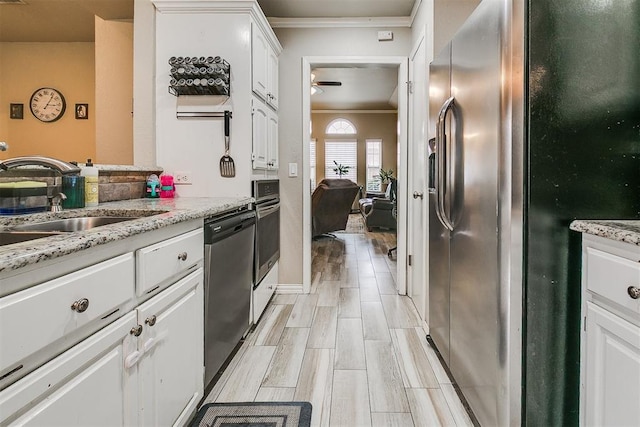 716 SW 149th Pl, Oklahoma City, OK 73170 - kitchen with white cabinets, a sink, appliances with stainless steel finishes, ceiling fan, and ornamental molding