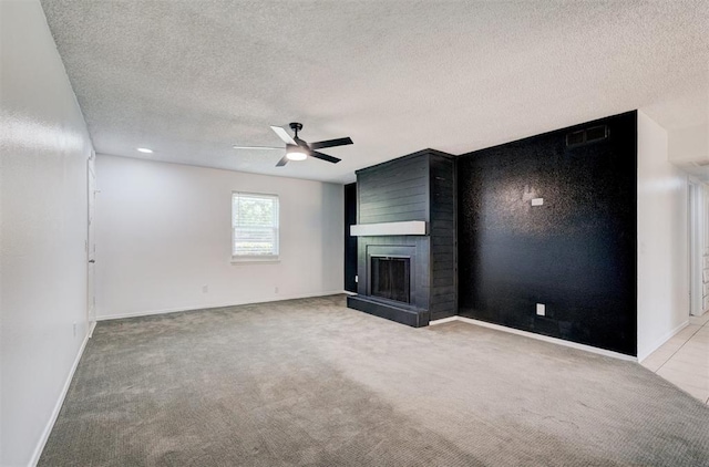 unfurnished living room featuring carpet floors, a textured ceiling, ceiling fan, and a large fireplace