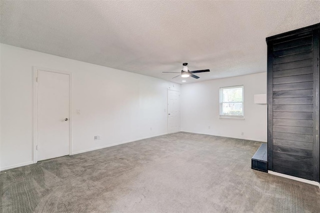 carpeted empty room with baseboards, a textured ceiling, and ceiling fan