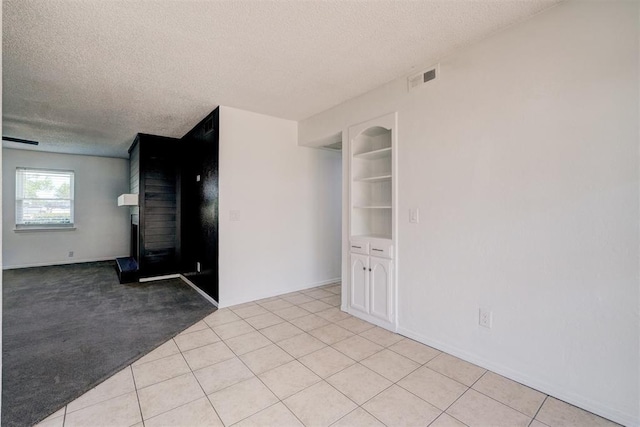 spare room featuring light tile patterned floors, a textured ceiling, and visible vents