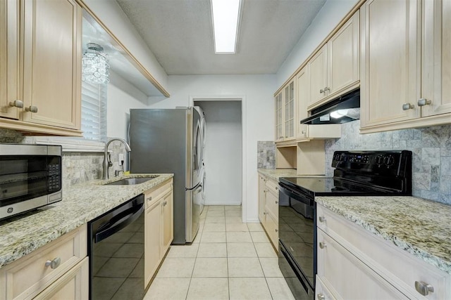 kitchen with under cabinet range hood, tasteful backsplash, light stone counters, a sink, and black appliances