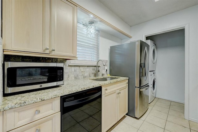 kitchen featuring backsplash, stacked washer and dryer, appliances with stainless steel finishes, a sink, and light tile patterned flooring