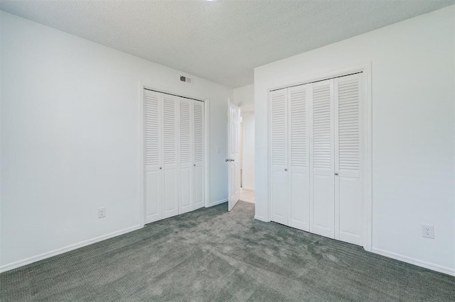 unfurnished bedroom with visible vents, carpet flooring, multiple closets, and baseboards