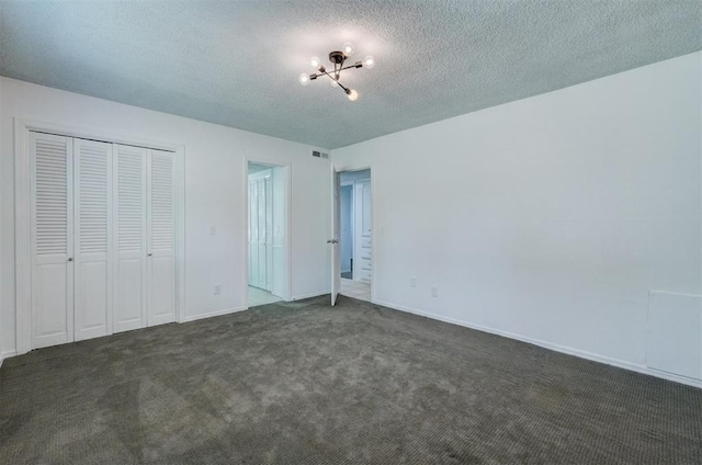 unfurnished bedroom featuring a textured ceiling, visible vents, baseboards, a notable chandelier, and carpet