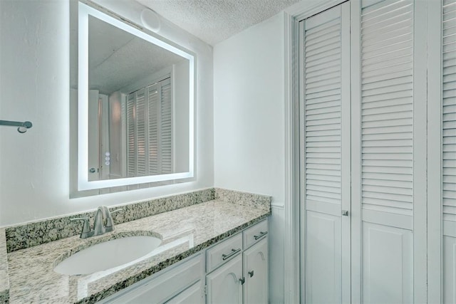 bathroom featuring a closet, a textured ceiling, and vanity