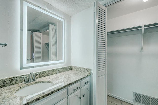 bathroom with a textured ceiling, visible vents, tile patterned floors, and vanity