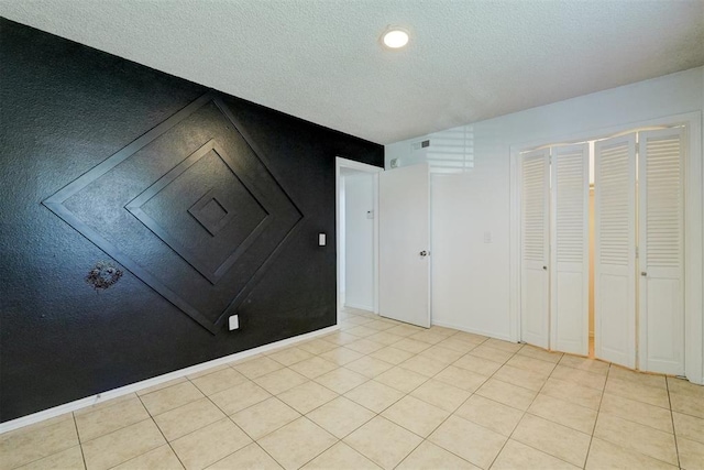unfurnished bedroom with a textured ceiling, visible vents, light tile patterned floors, and a closet