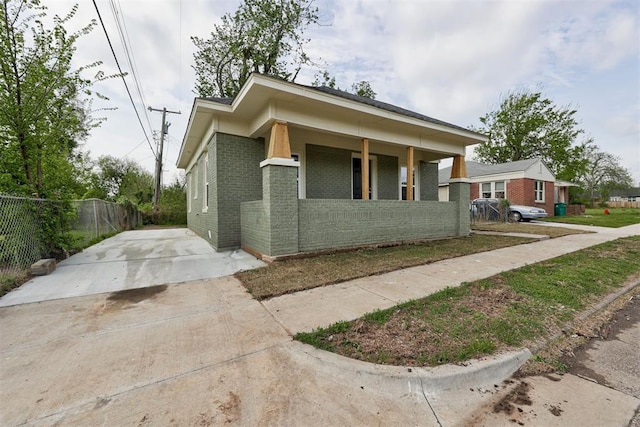 1608 NE 21st St, Oklahoma City, OK 73111 - view of front facade featuring brick siding, concrete driveway, covered porch, and fence