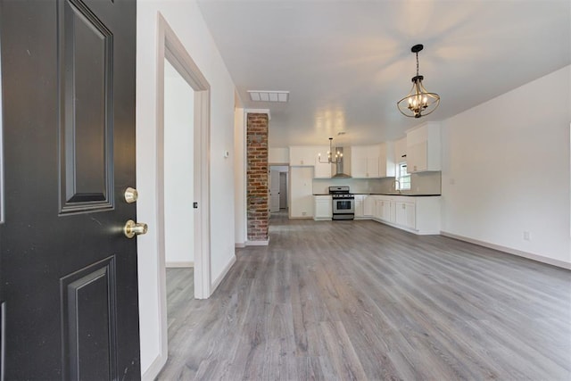 1608 NE 21st St, Oklahoma City, OK 73111 - unfurnished living room with light wood-type flooring, visible vents, baseboards, and a notable chandelier