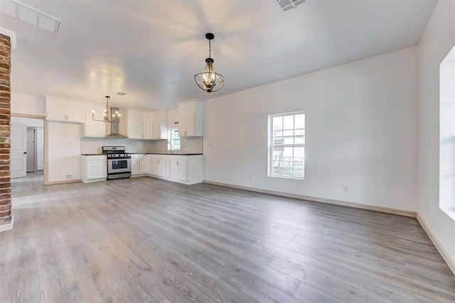 1608 NE 21st St, Oklahoma City, OK 73111 - unfurnished living room with visible vents, light wood finished floors, a sink, and an inviting chandelier