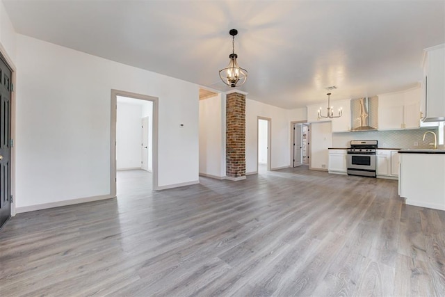 1608 NE 21st St, Oklahoma City, OK 73111 - unfurnished living room with light wood-style flooring, baseboards, a sink, and a chandelier