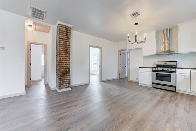 1608 NE 21st St, Oklahoma City, OK 73111 - kitchen with wall chimney exhaust hood, visible vents, gas range, and an inviting chandelier
