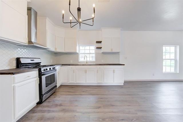 1608 NE 21st St, Oklahoma City, OK 73111 - kitchen featuring wall chimney range hood, open shelves, light wood-style floors, gas range, and an inviting chandelier