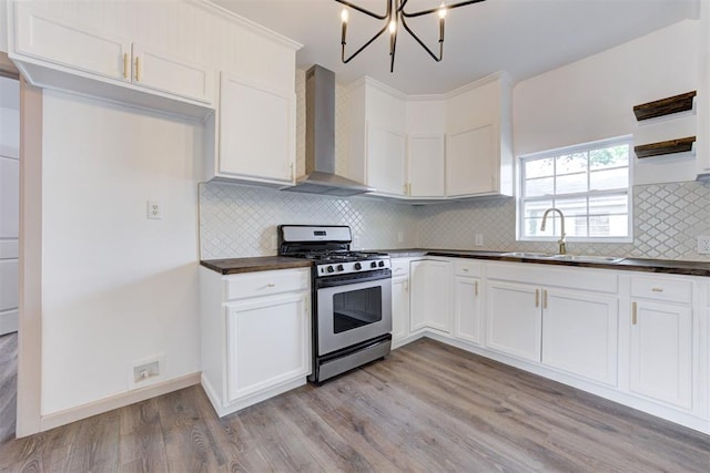 1608 NE 21st St, Oklahoma City, OK 73111 - kitchen featuring light wood finished floors, a sink, dark countertops, wall chimney range hood, and stainless steel gas range oven