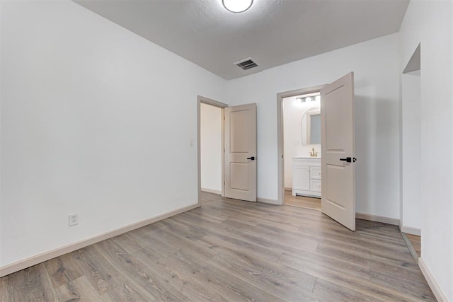 1608 NE 21st St, Oklahoma City, OK 73111 - unfurnished bedroom with ensuite bath, baseboards, visible vents, and light wood-type flooring