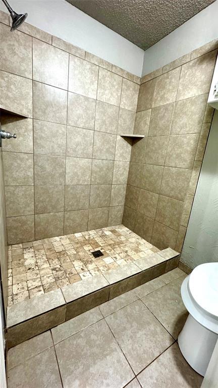 2900 Pheasant Run, Edmond, OK 73012 - bathroom with tiled shower, tile patterned floors, and toilet