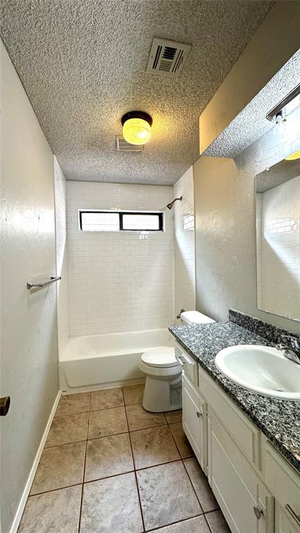 2900 Pheasant Run, Edmond, OK 73012 - full bathroom featuring vanity, toilet, tile patterned flooring, tub / shower combination, and a textured ceiling