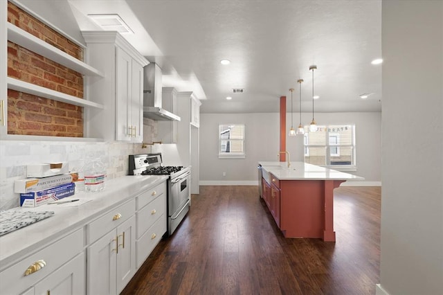 kitchen with open shelves, stainless steel gas range, a healthy amount of sunlight, and wall chimney range hood