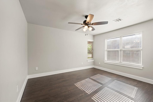 empty room with baseboards, visible vents, ceiling fan, and dark wood-type flooring