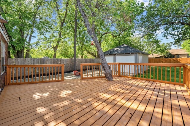 wooden terrace featuring a fenced backyard, a detached garage, and an outbuilding